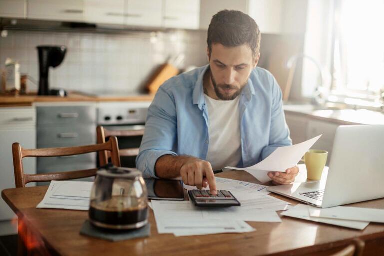 Homem calculando a antecipação de recebíveis por cartão de crédito.